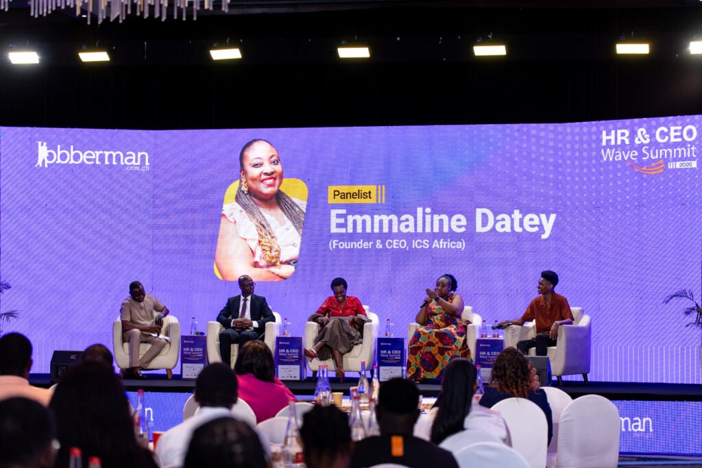 Emaline Datey speaking into a microphone on stage during a panel discussion at the Jobberman Ghana HR and CEO Wave Summit 2026.