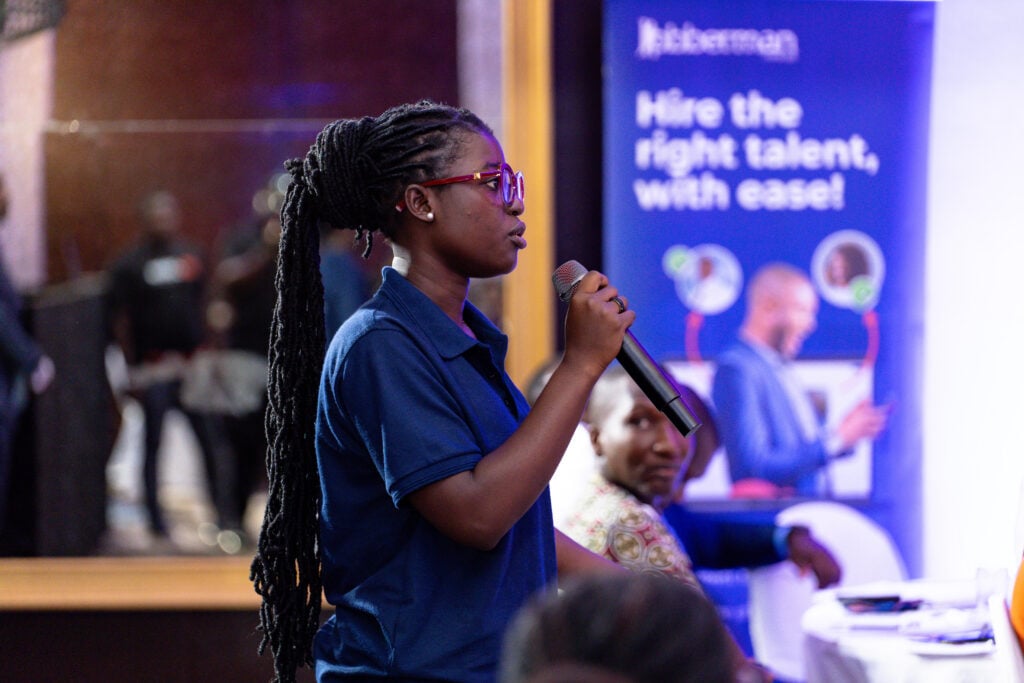 An event attendee holding a microphone and asking a question to the panelists during the Jobberman Ghana HR and CEO Wave Summit 2026.